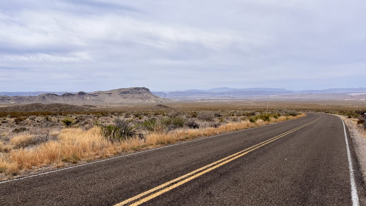 an empty highway winds through desert landscape